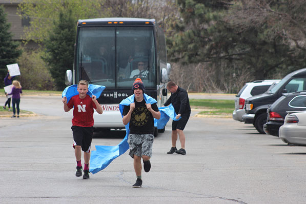 Fans of Bellevue West Winterguard run in front of the bus with two rivers to welcome home the newly crowned World Champion team.