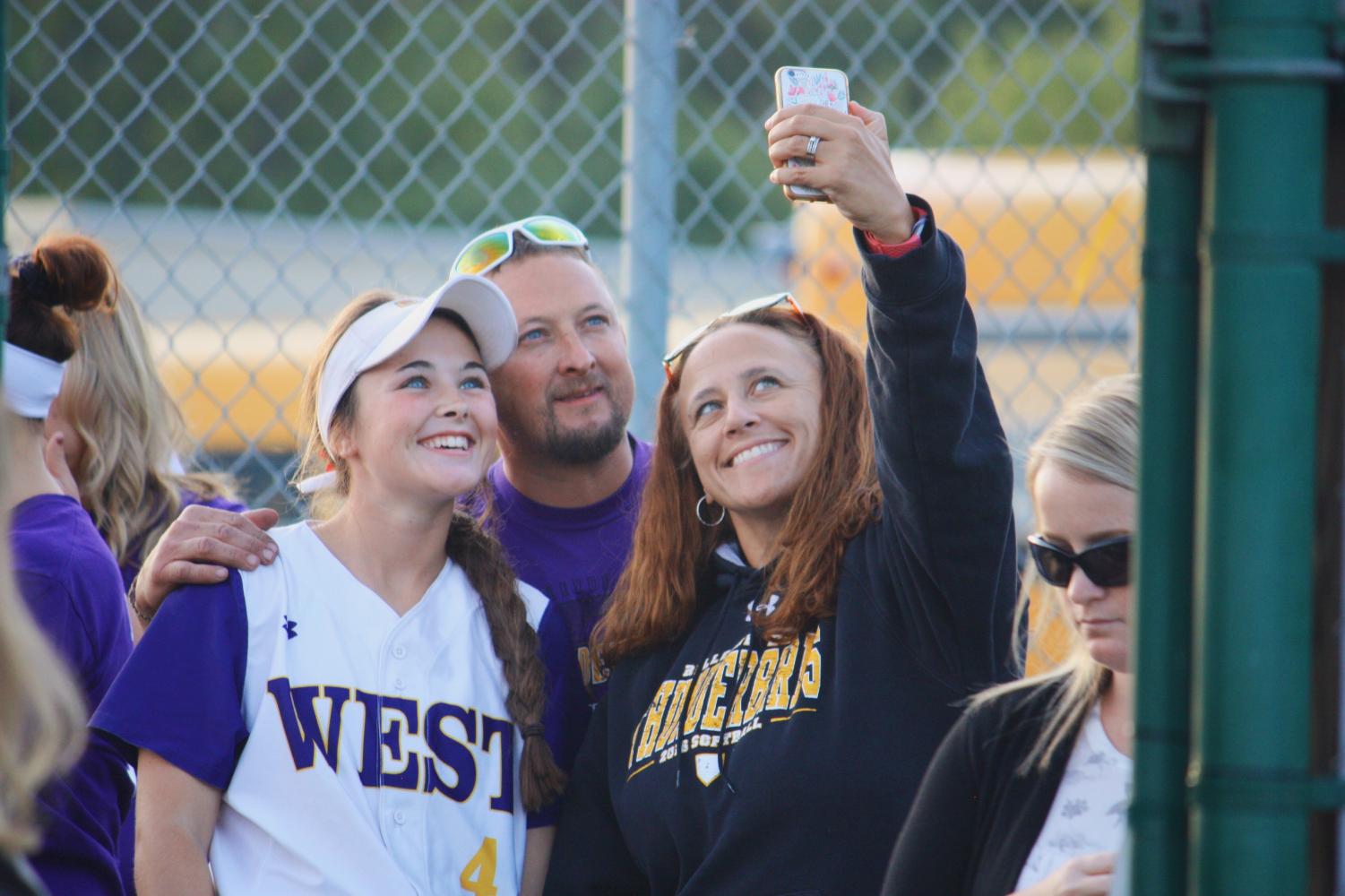 Kortney Buresh poses for a picture with her parents during softball senior night.