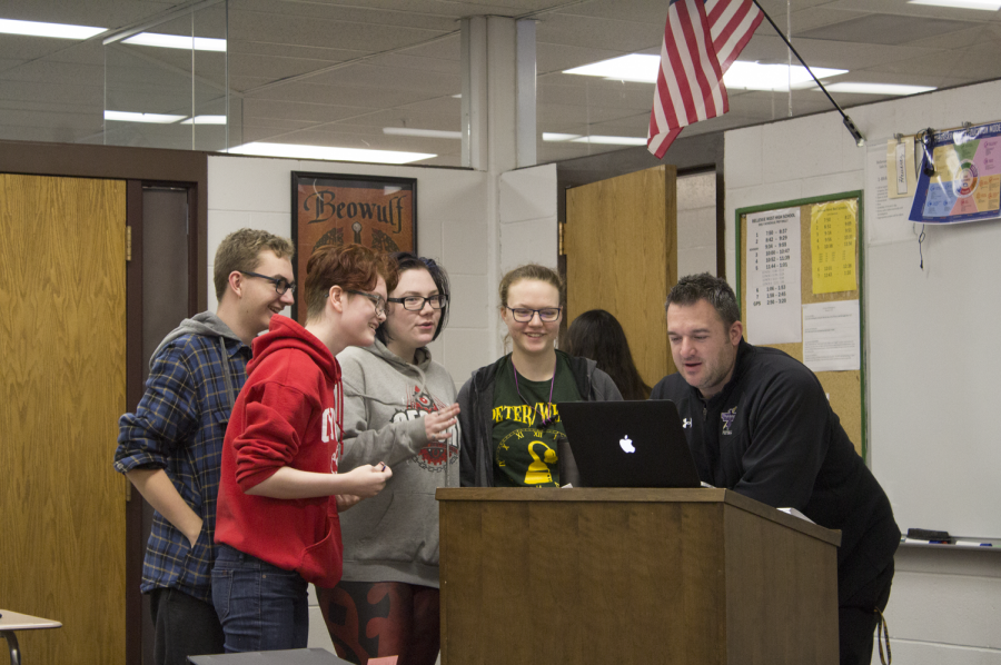 Adam Heuertz consults with students in his first hour English 12 A class about their poetry project.  Next year, English 12 A will no longer be available along with other advanced classes.