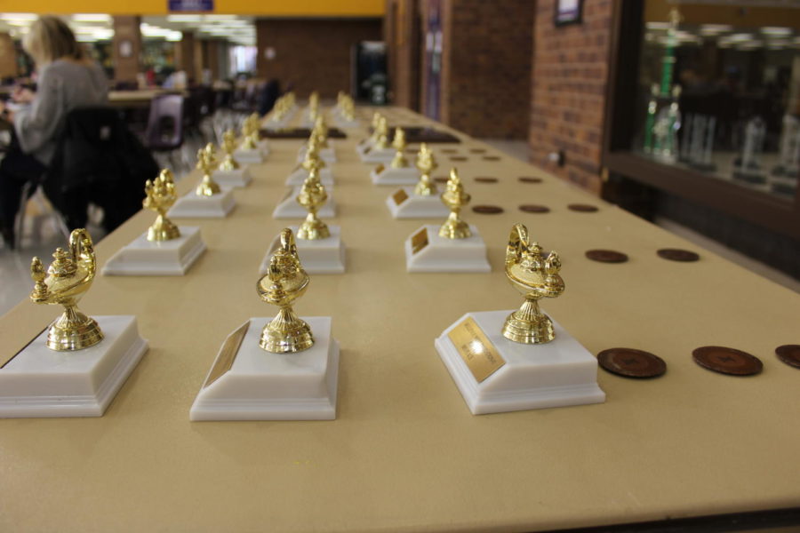 Trophies are lined up on a table in the cafeteria in preparation for the awards ceremony.
