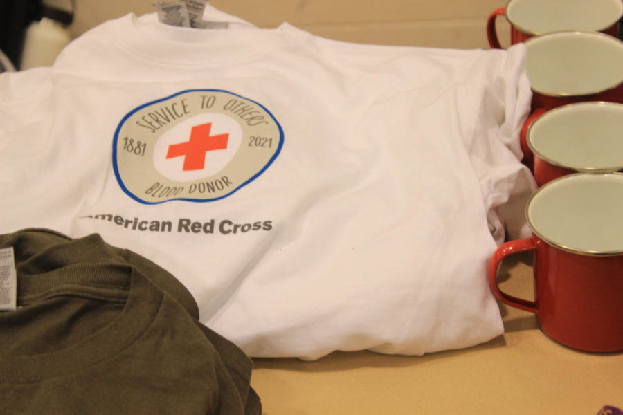 A table of merchandise from the Red Cross is offered for blood donors.
