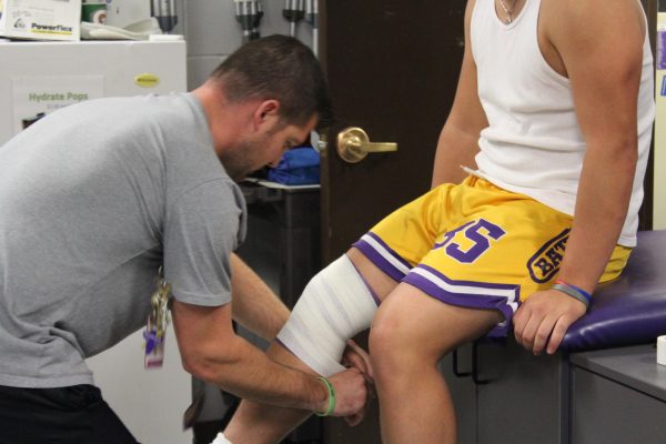 Athletic Trainer Jeremy Langer wraps a student’s knee before practice.