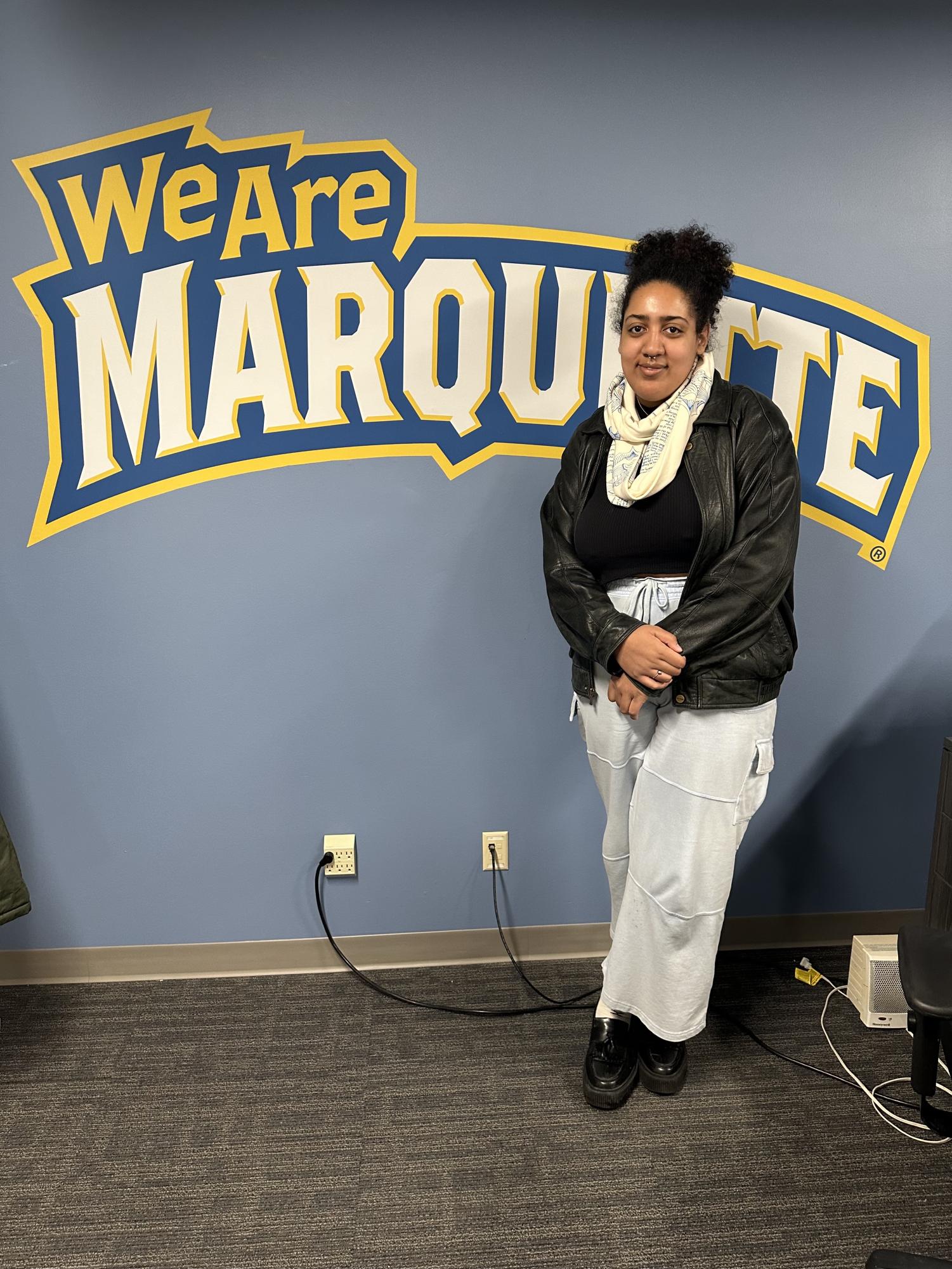 2022 alum Gnally Boukar poses in front of the Marquette sign in the Urban Scholars lounge. Photo provided by Gnally Boukar.