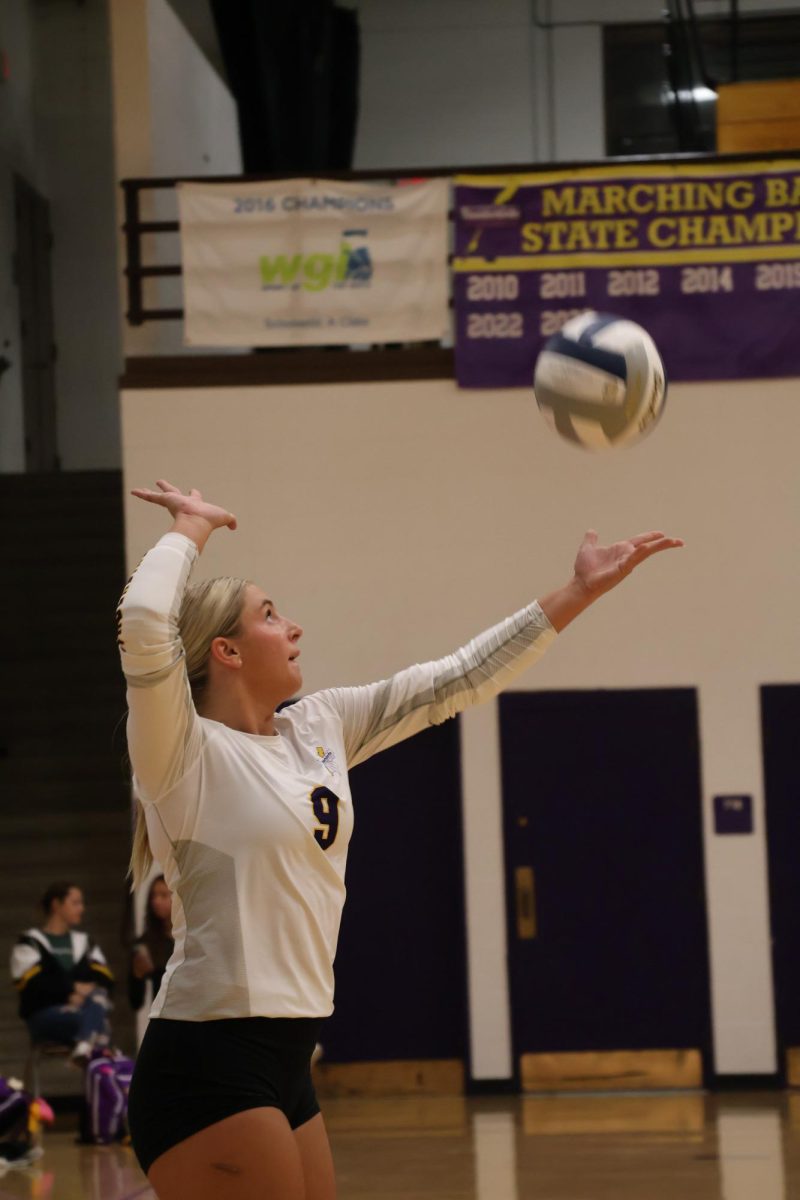 Senior Anna Faiman throws the ball up to serve.