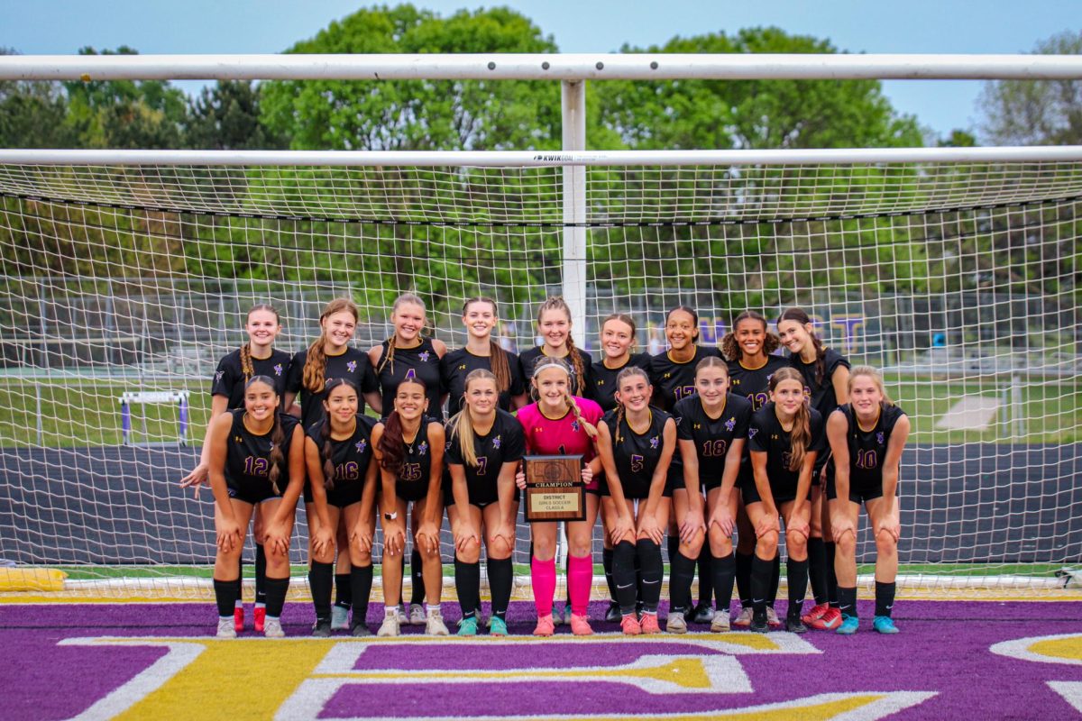 The girls soccer team pose for a photo together with the district championship plaque.