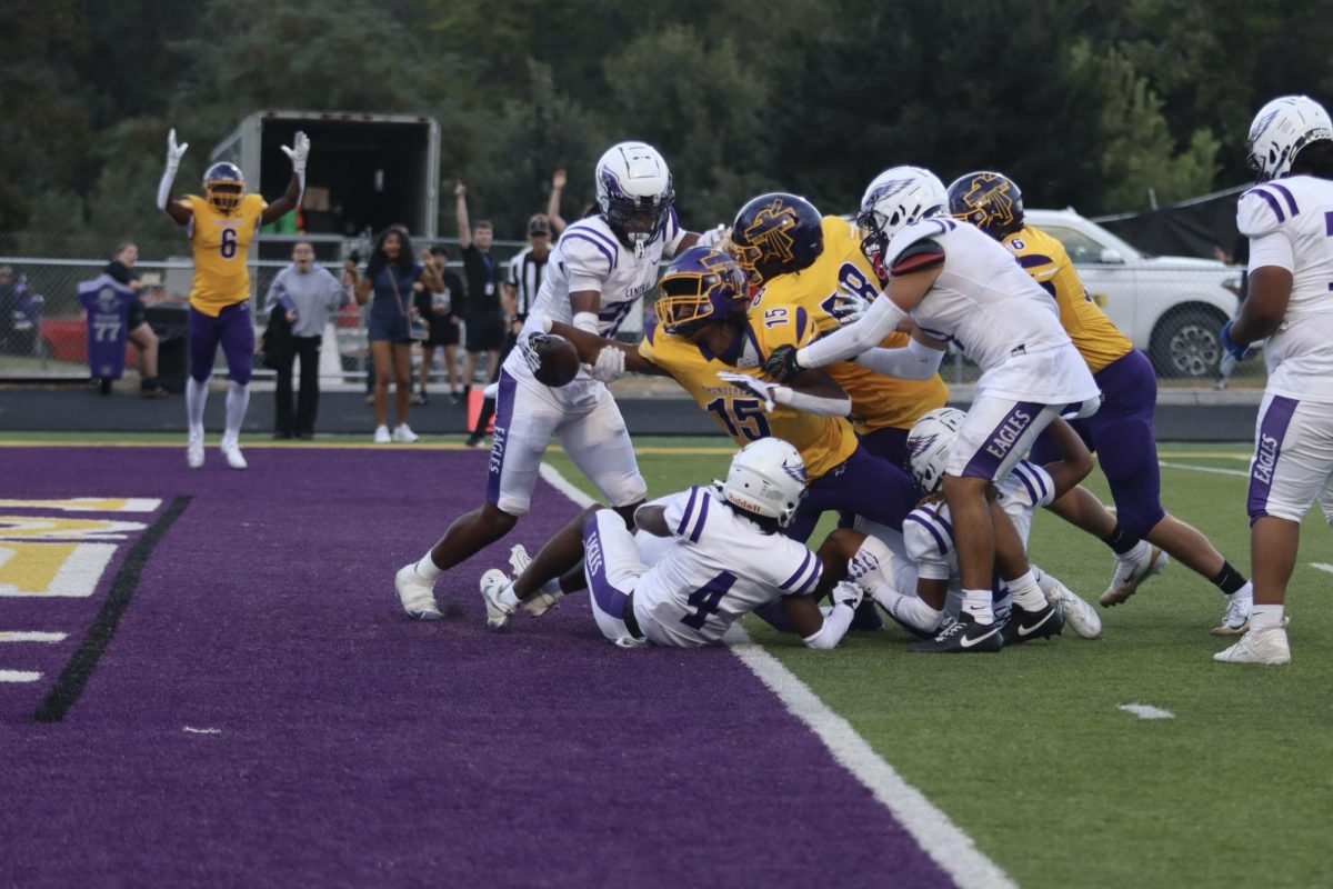 Junior Tristan Gerez-James reaches across opponents to score a touchdown.