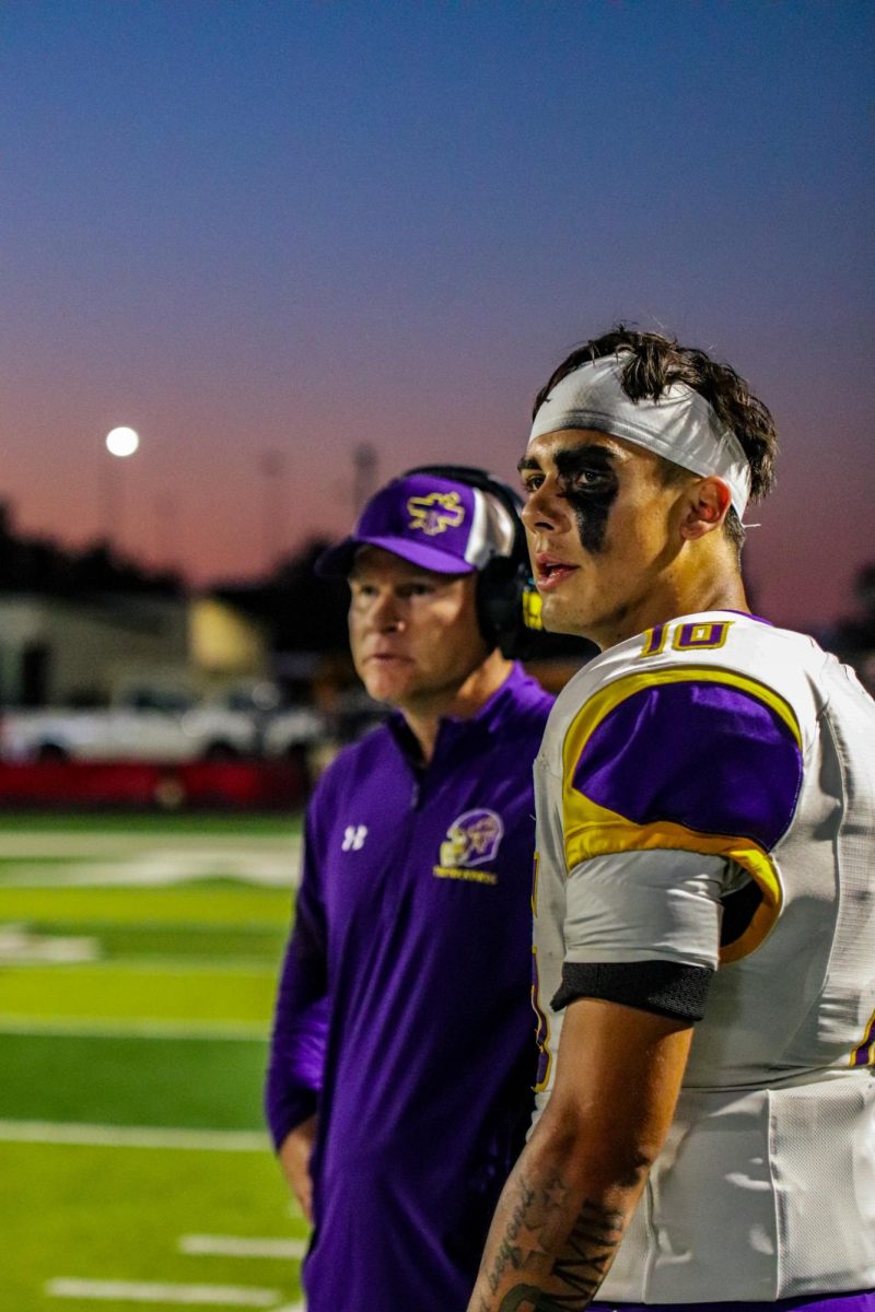 Senior Will Anderson talks to Coach Michael Huffman while defense makes plays.