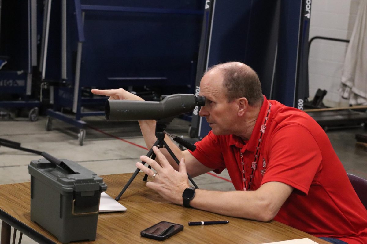 Stephen Vanderhoof examines his student’s work from afar using a small telescope.
